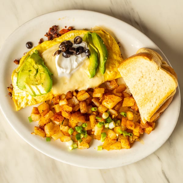 Omelet with cheese, avocado, olives, and sour cream, served with home fries and toast.