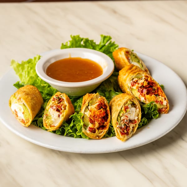 Crispy egg rolls filled with avocado, cream cheese, and sun-dried tomatoes, served with dipping sauce.
