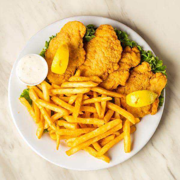 Golden fried fish fillets and french fries with lemon wedges and tartar sauce on a white plate.