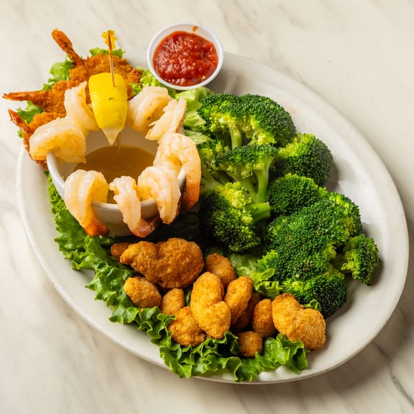 A platter of fried shrimp, popcorn shrimp, boiled shrimp, broccoli, cocktail sauce, and butter.